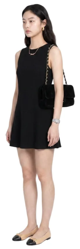 A black sleeveless mini dress with two-tone flats and a small shoulder bag.